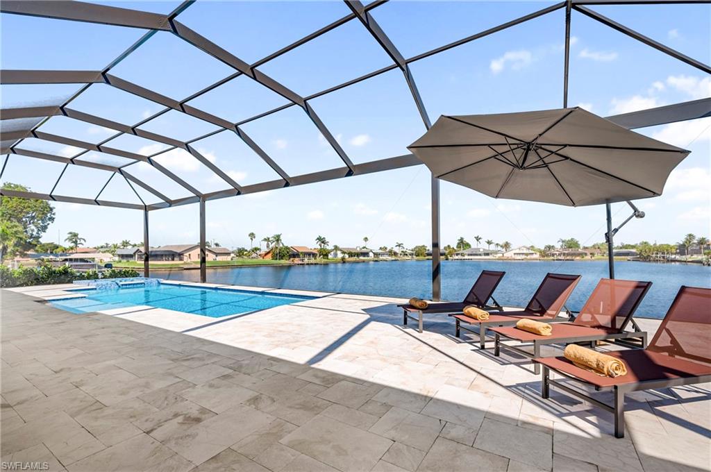 Outdoor pool with glass enclosure, a patio area, and a water view