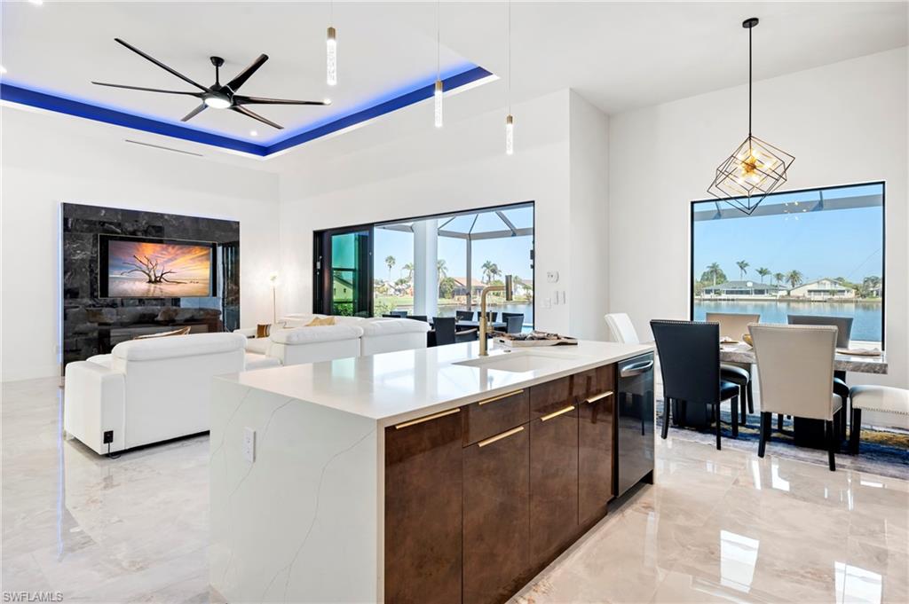 Kitchen with marble finish floor, modern cabinets, a tray ceiling, dark brown cabinets, and ceiling fan
