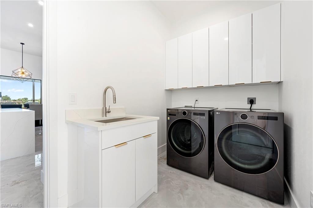 Laundry room featuring washer and clothes dryer, cabinet space, and a sink