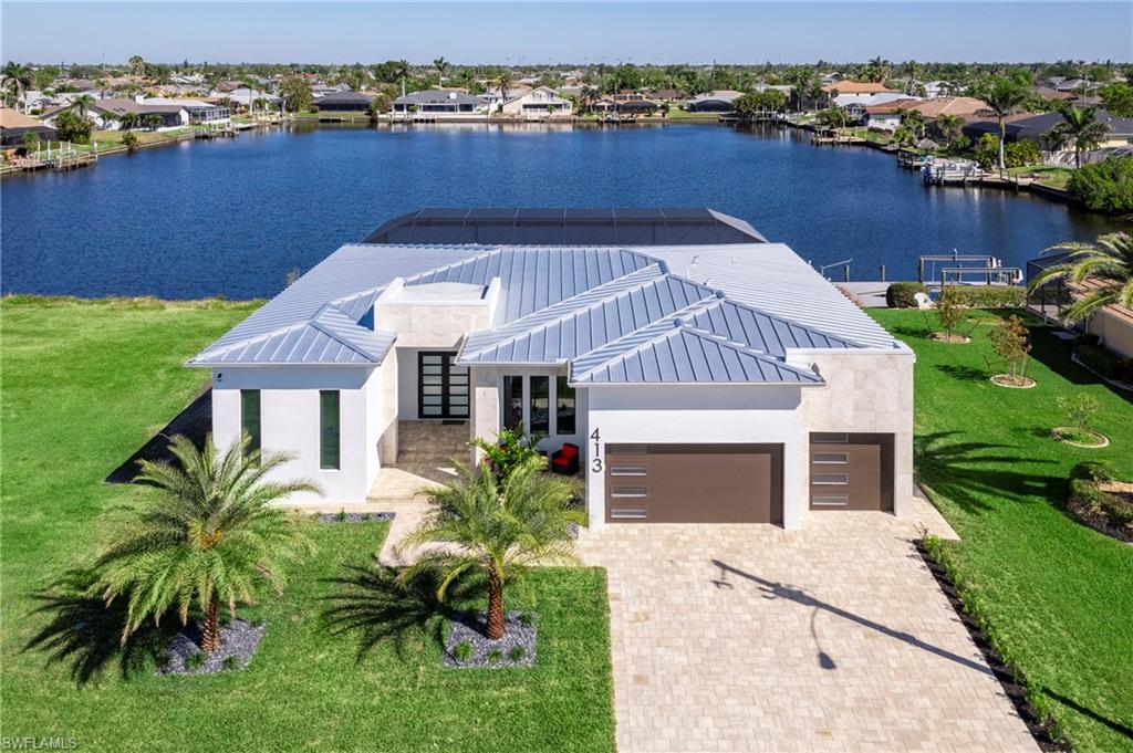 View of front of property with stucco siding, a water view, decorative driveway, a residential view, and an attached garage