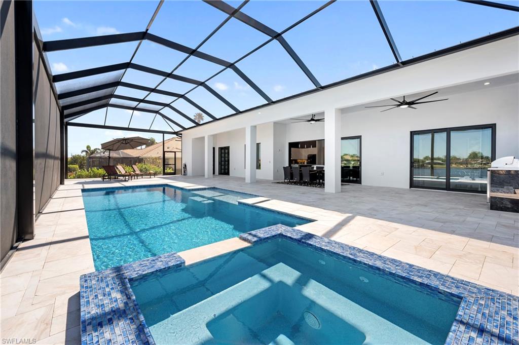 View of swimming pool with a patio area, glass enclosure, a pool with connected hot tub, and outdoor dining area