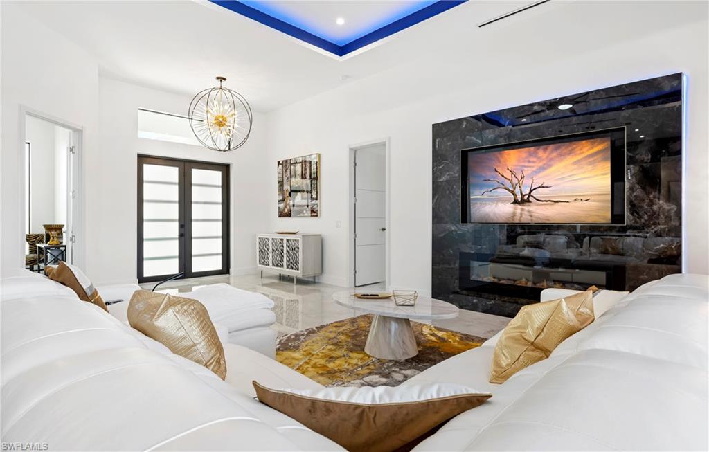 Living area with a chandelier, french doors, a fireplace, and baseboards