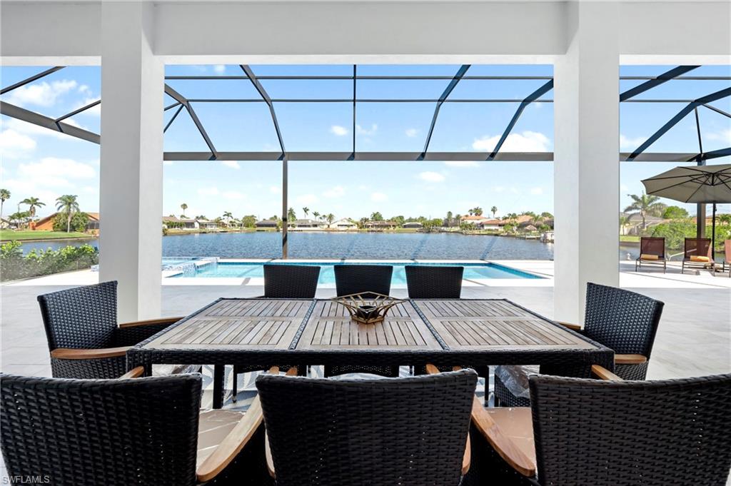 View of patio with an outdoor pool, glass enclosure, a water view, and outdoor dining space