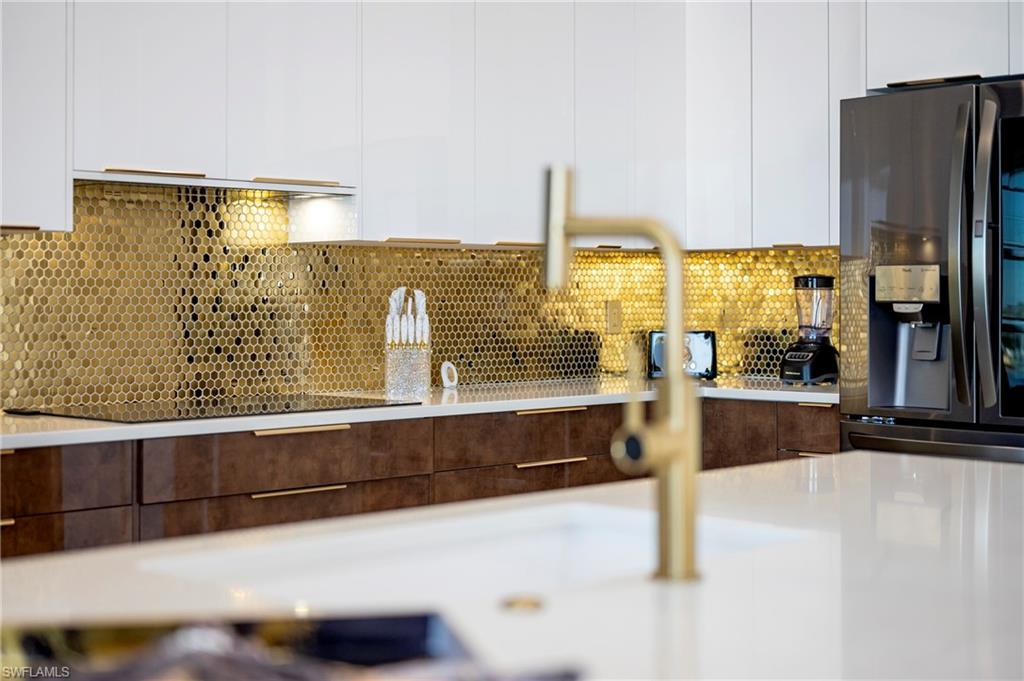 Interior details with tasteful backsplash, refrigerator with ice dispenser, white cabinetry, and modern cabinets