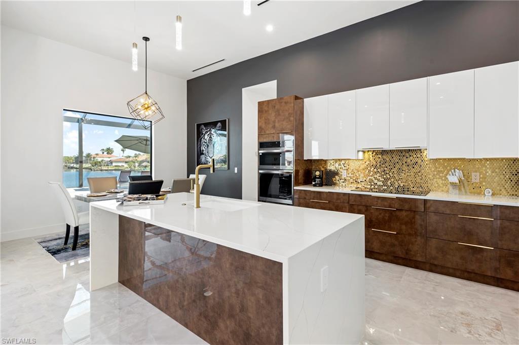 Kitchen featuring stainless steel double oven, black electric stovetop, modern cabinets, and white cabinetry