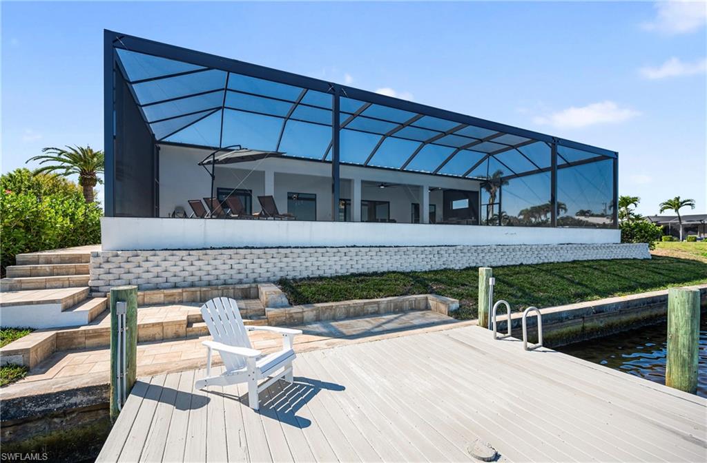 View of dock with a lanai, a yard, and a water view