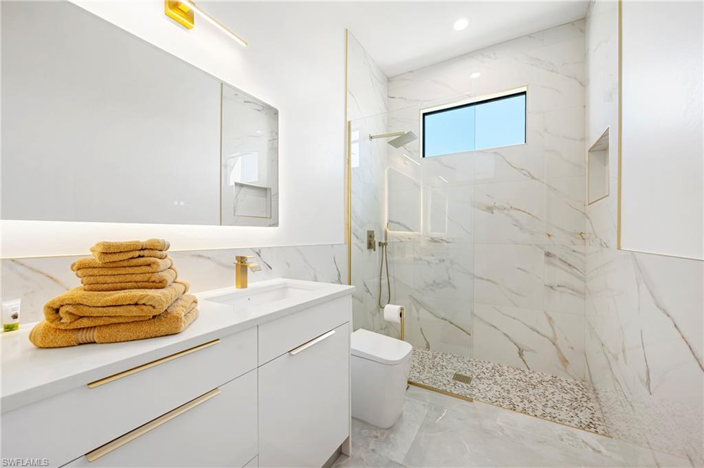 Full bath featuring a marble finish shower, toilet, recessed lighting, marble finish floor, and vanity
