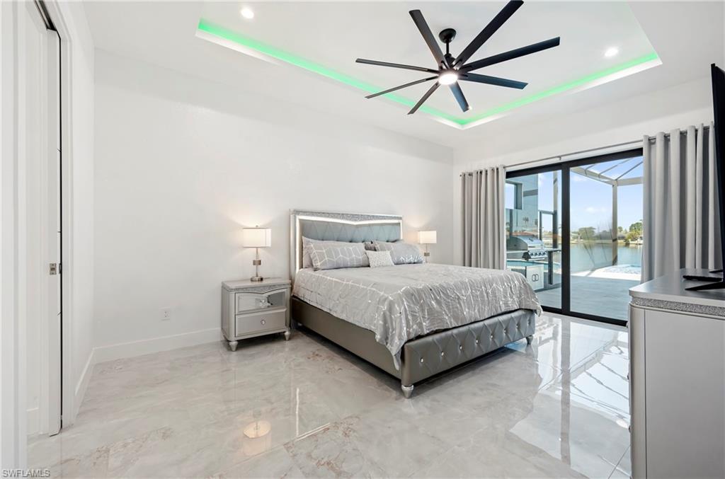 Bedroom featuring a raised ceiling, recessed lighting, access to exterior, and baseboards