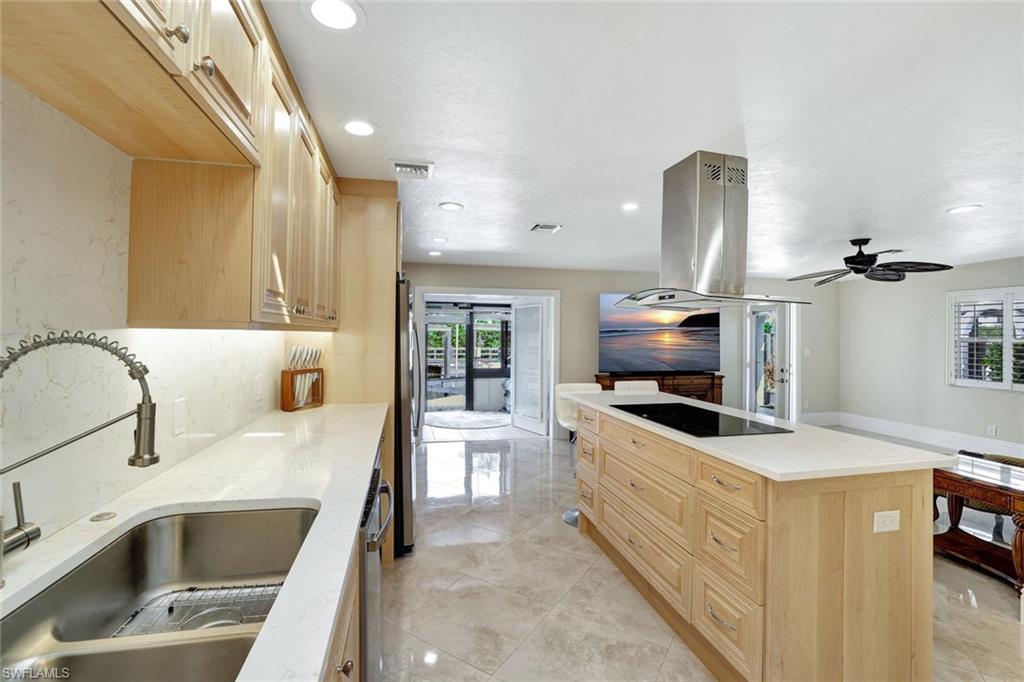 Kitchen with appliances with stainless steel finishes, light brown cabinetry, island exhaust hood, a center island, and sink