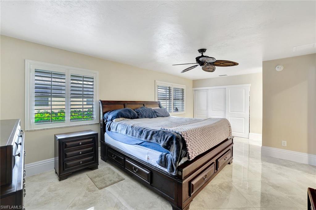 Bedroom with ceiling fan, a textured ceiling, and a closet