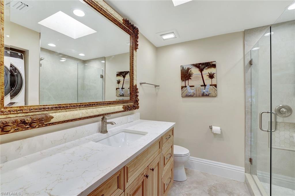 Bathroom featuring a shower with shower door, vanity, a skylight, tile patterned flooring, and toilet