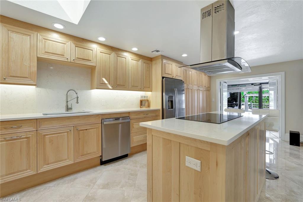 Kitchen with appliances with stainless steel finishes, island exhaust hood, light brown cabinets, a kitchen island, and sink