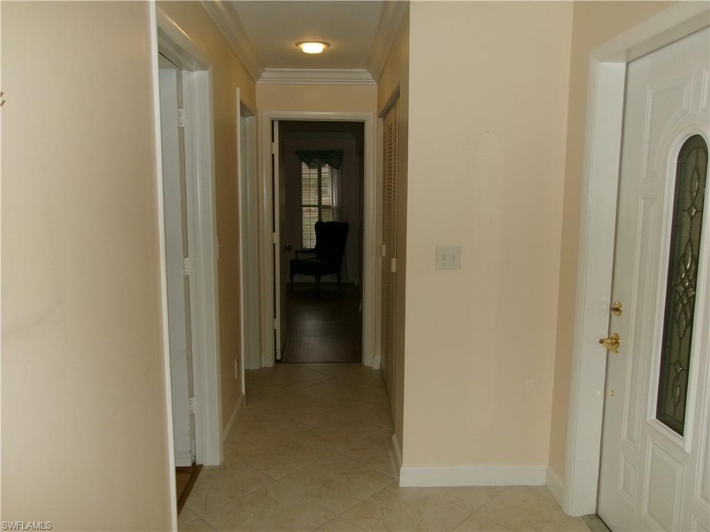 Corridor featuring light tile patterned flooring, crown molding, and baseboards