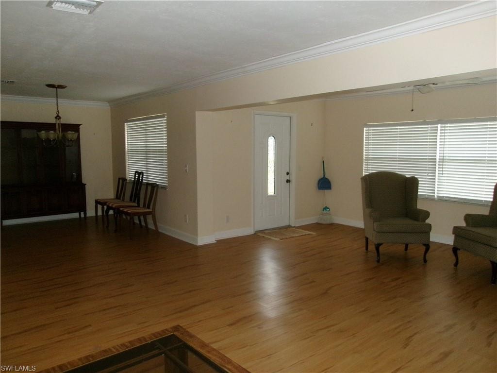 Foyer featuring an inviting chandelier, baseboards, ornamental molding, and wood finished floors