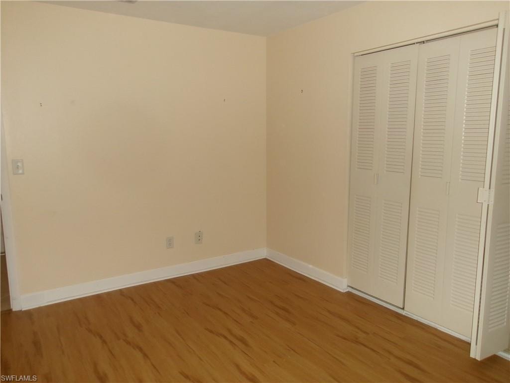 Unfurnished bedroom with a closet, wood finished floors, and baseboards