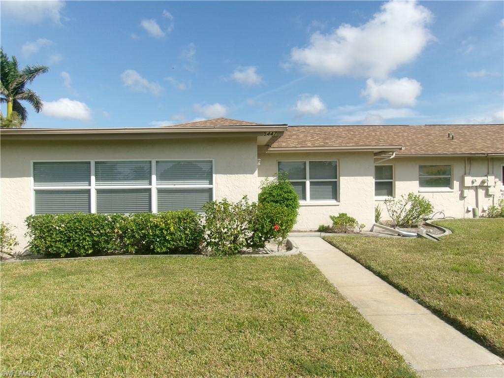 View of front of house with a shingled roof, a front yard, and stucco siding
