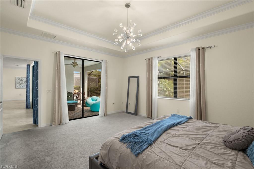 Carpeted bedroom featuring a chandelier, a tray ceiling, access to outside, and ornamental molding