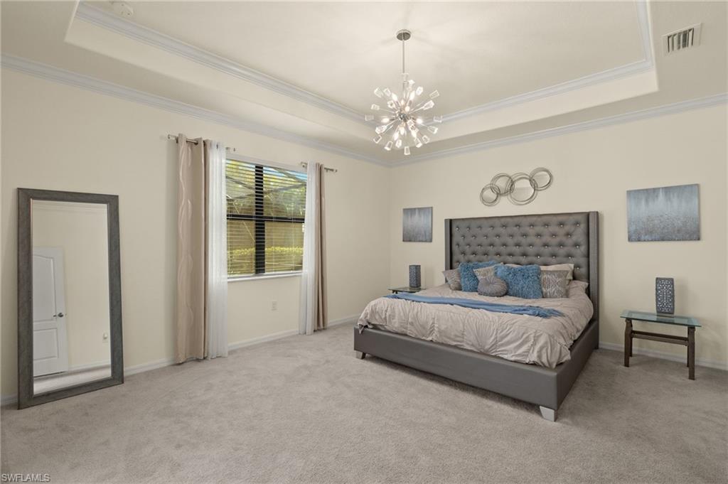 Bedroom with crown molding, a raised ceiling, light colored carpet, and an inviting chandelier