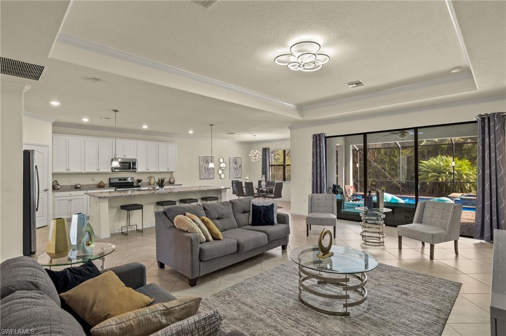Tiled living room featuring a tray ceiling, ornamental molding, and a textured ceiling