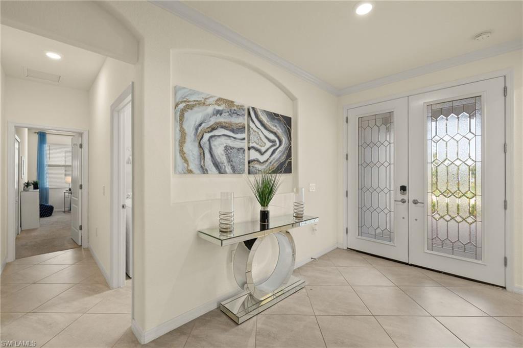 Foyer featuring ornamental molding, light tile patterned floors, french doors, and a healthy amount of sunlight