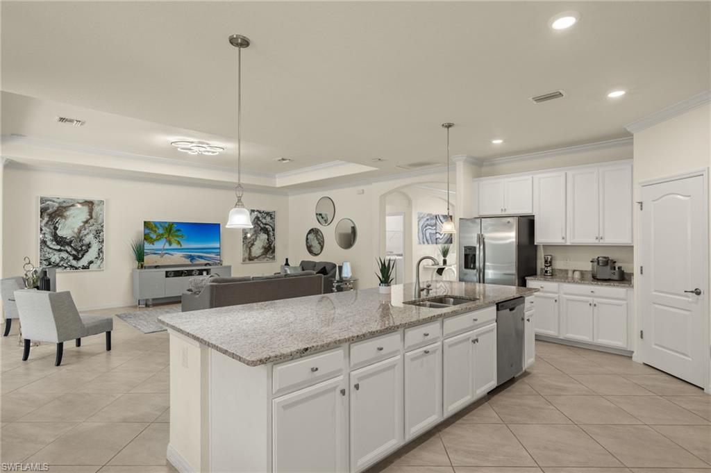 Kitchen with appliances with stainless steel finishes, sink, white cabinetry, and a kitchen island with sink