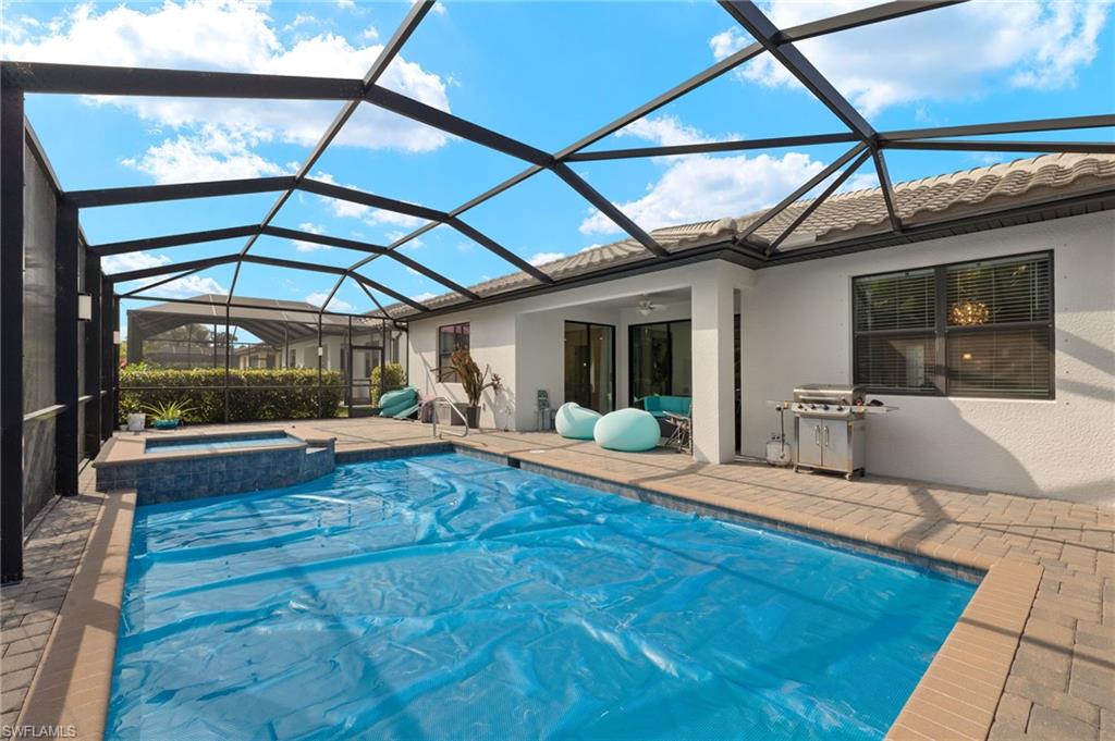 View of pool with an in ground hot tub, a patio, glass enclosure, and ceiling fan