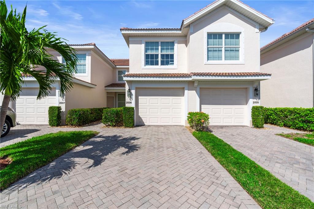 View of front facade featuring decorative driveway, an attached garage, a tile roof, and stucco siding