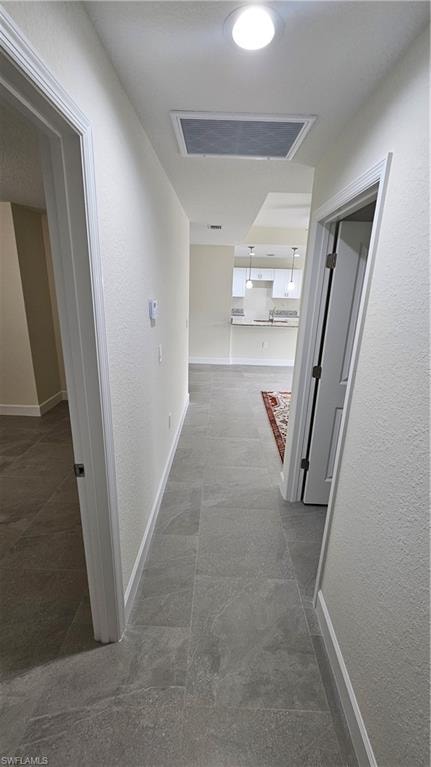 Hall featuring baseboards and a textured wall