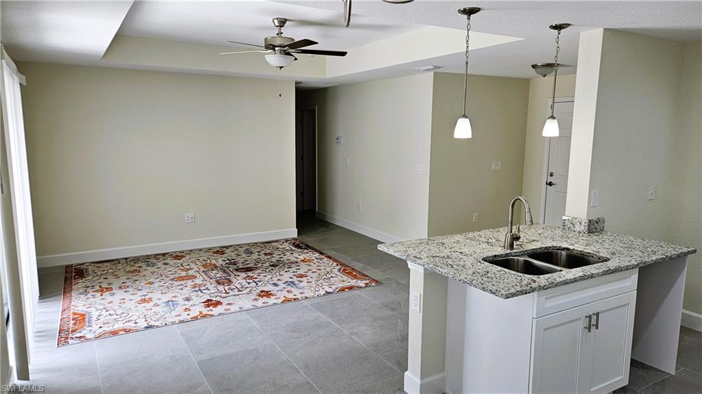 Kitchen featuring a sink, a ceiling fan, baseboards, decorative light fixtures, and white cabinetry