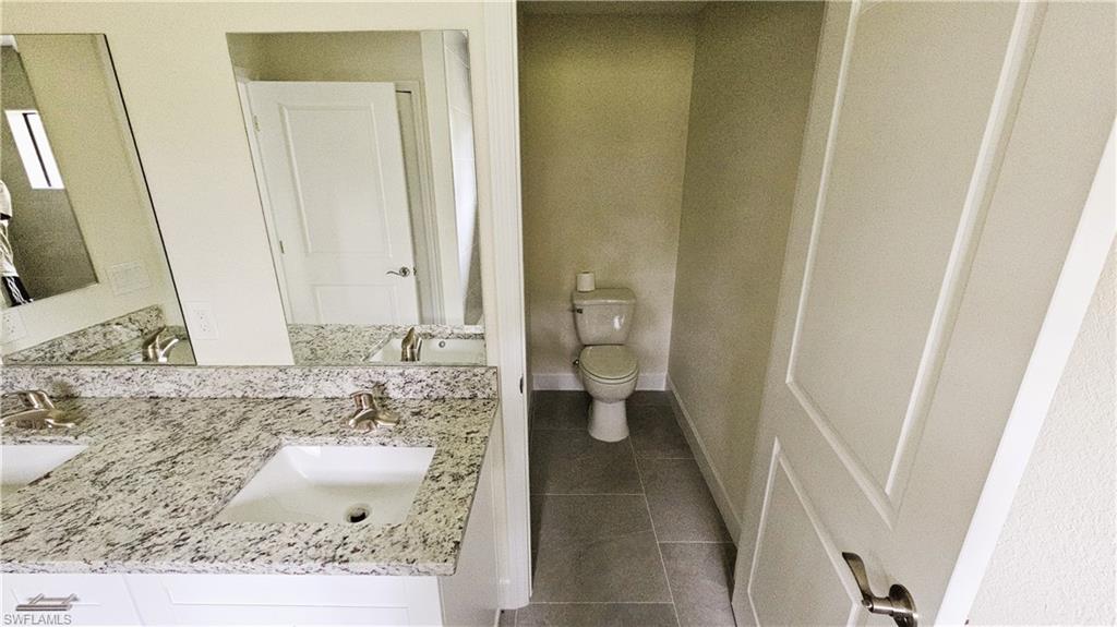 Full bathroom featuring tile patterned floors, toilet, and double vanity