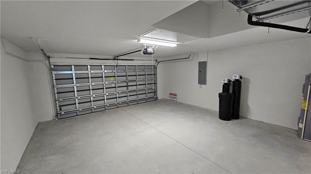 Garage with electric panel, water heater, and a garage door opener
