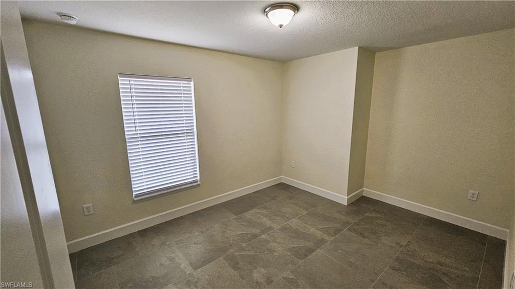 Spare room featuring a textured ceiling and baseboards