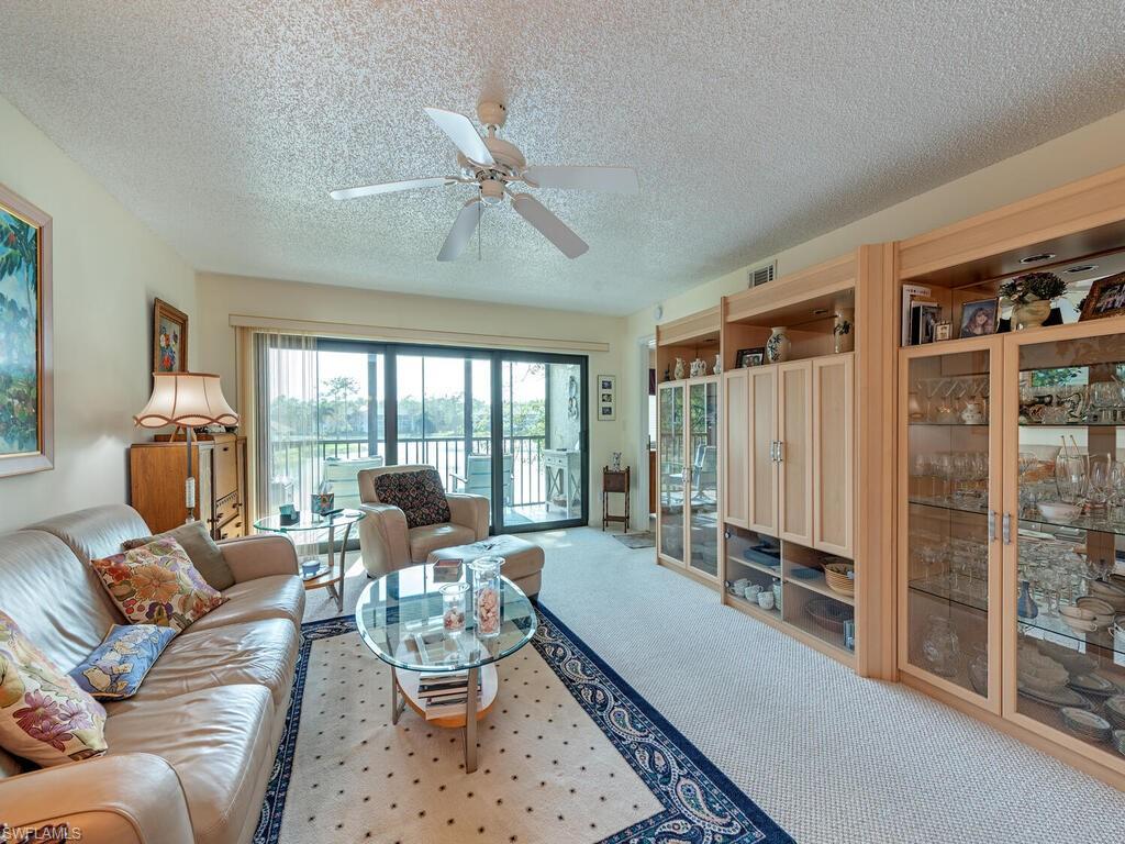 Living area with light carpet, ceiling fan, a textured ceiling, and visible vents