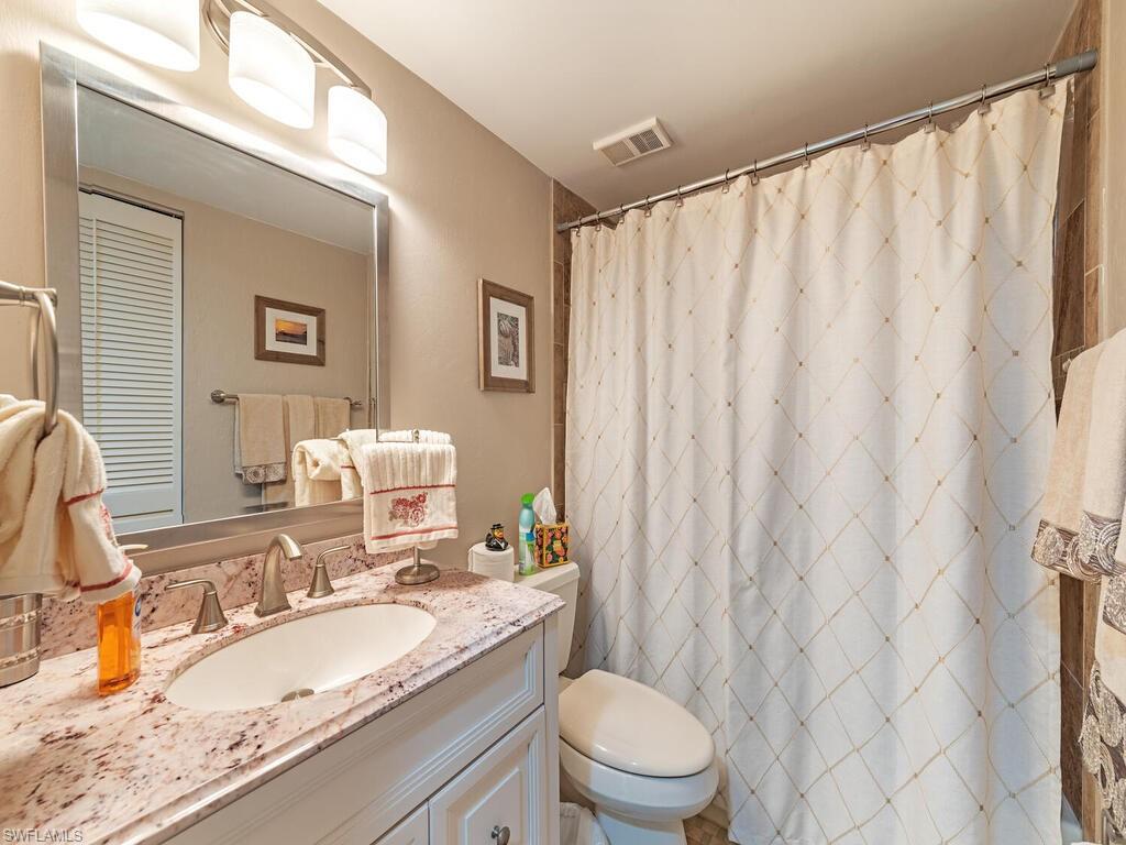 Full bath with toilet, vanity, visible vents, a closet, and a shower with curtain