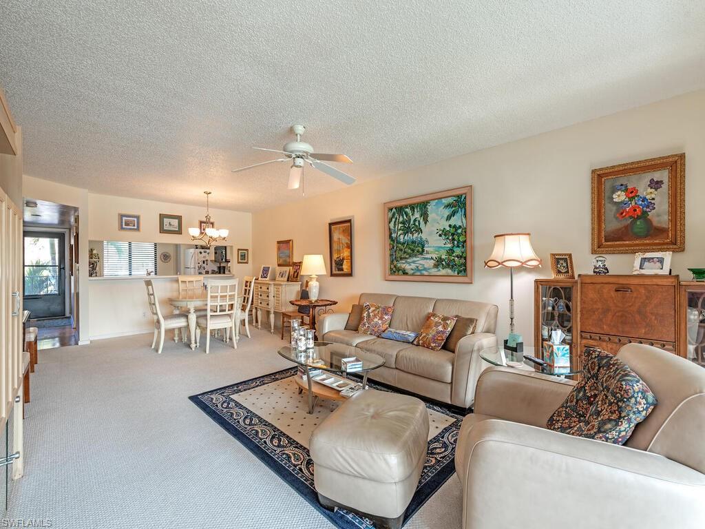 Living room with carpet floors, a textured ceiling, and ceiling fan with notable chandelier