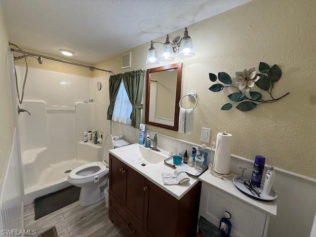 Full bath with visible vents, a textured wall, wood finished floors, a textured ceiling, and a shower stall