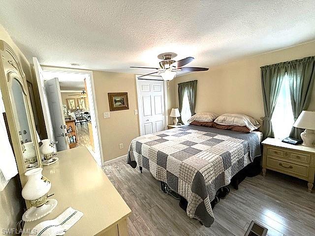 Bedroom with ceiling fan, a textured ceiling, visible vents, a closet, and dark wood finished floors