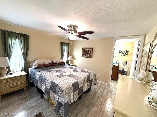 Bedroom with a textured ceiling, ceiling fan, dark wood-style flooring, and baseboards