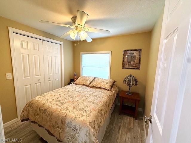Bedroom featuring a closet, a ceiling fan, a textured ceiling, wood finished floors, and baseboards