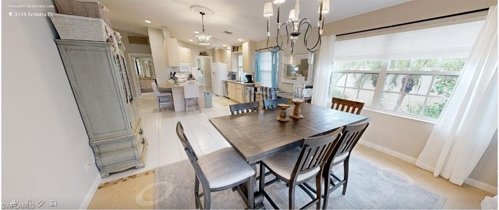 Kitchen with a ceiling fan, open floor plan, a peninsula, white appliances, and a kitchen breakfast bar