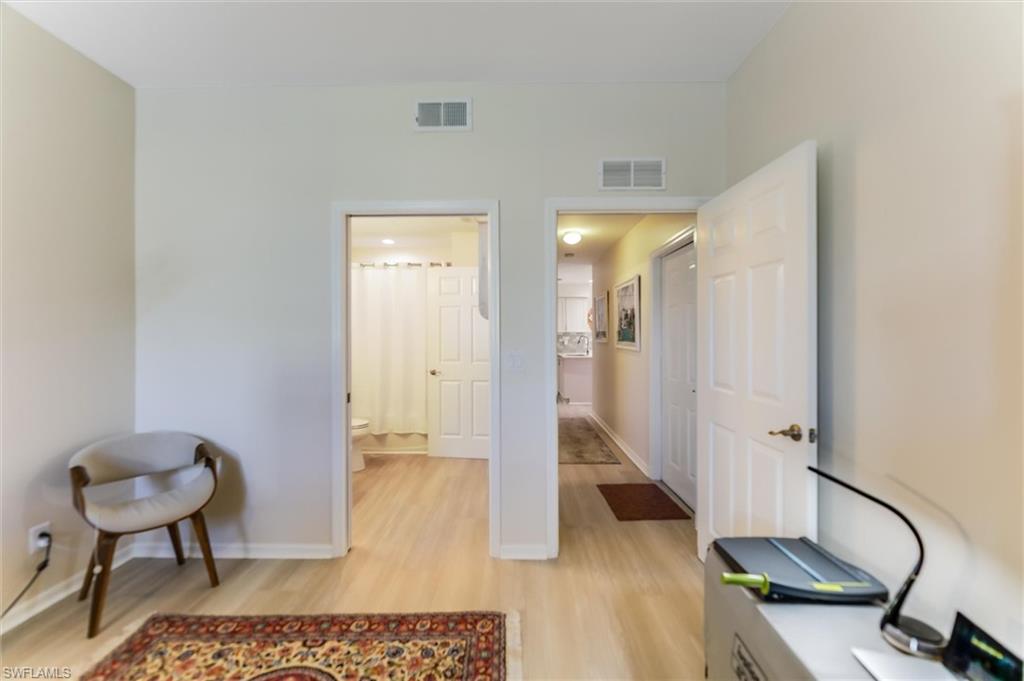 Office space with light wood-style flooring, visible vents, and baseboards