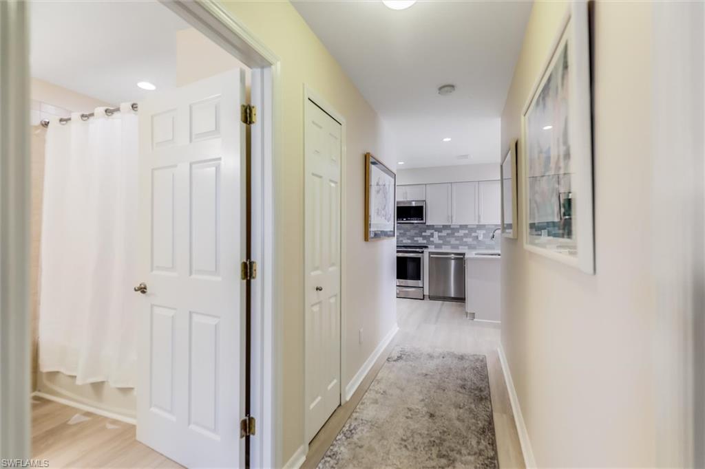 Corridor featuring baseboards, recessed lighting, a sink, and light wood-style floors