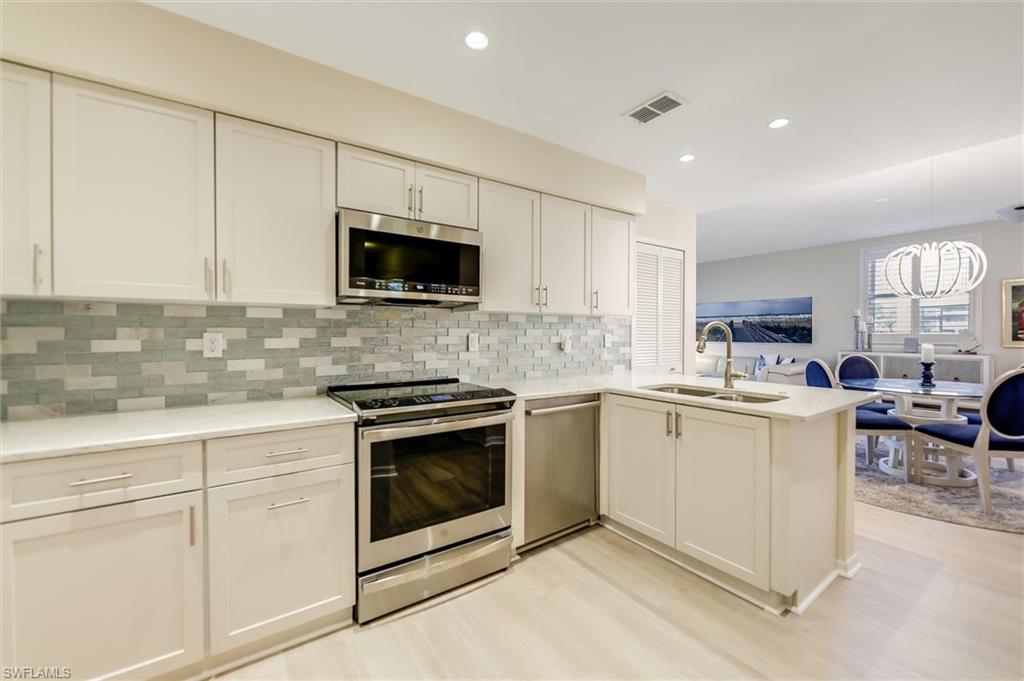 Kitchen with a peninsula, appliances with stainless steel finishes, light countertops, and a sink