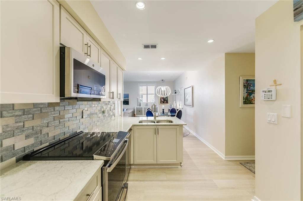 Kitchen with tasteful backsplash, visible vents, appliances with stainless steel finishes, a peninsula, and a sink