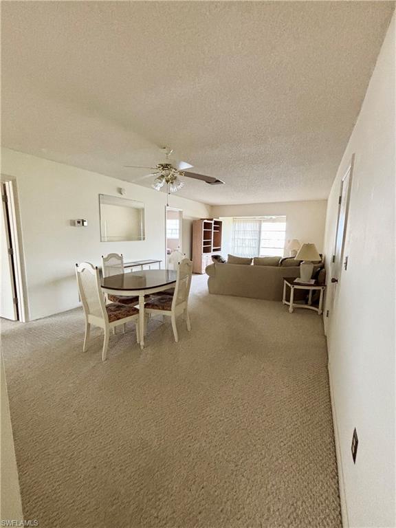 Dining space featuring ceiling fan, a textured ceiling, and carpet flooring