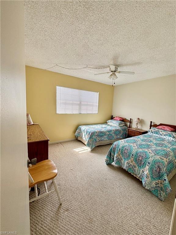 Carpeted bedroom featuring a textured ceiling and a ceiling fan