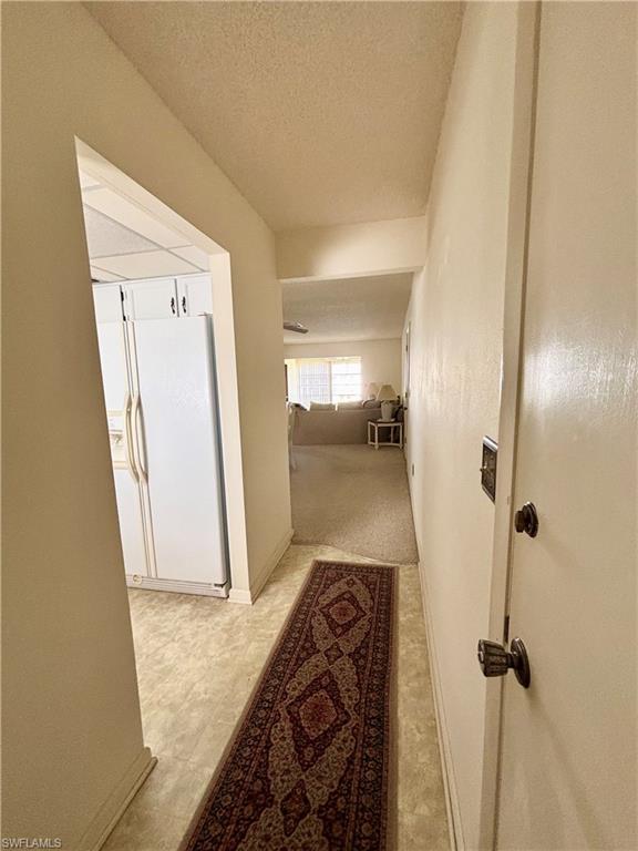 Hall with carpet and a textured ceiling
