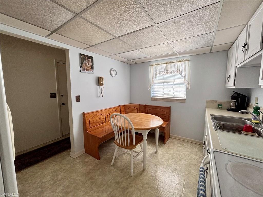 Dining space featuring a paneled ceiling, baseboards, and light floors