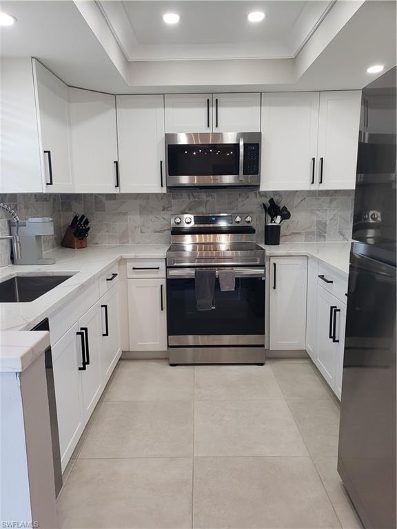 Remodeled Kitchen featuring quartz countertops, white shaker style cabinetry, stainless steel appliances and a tiled backsplash