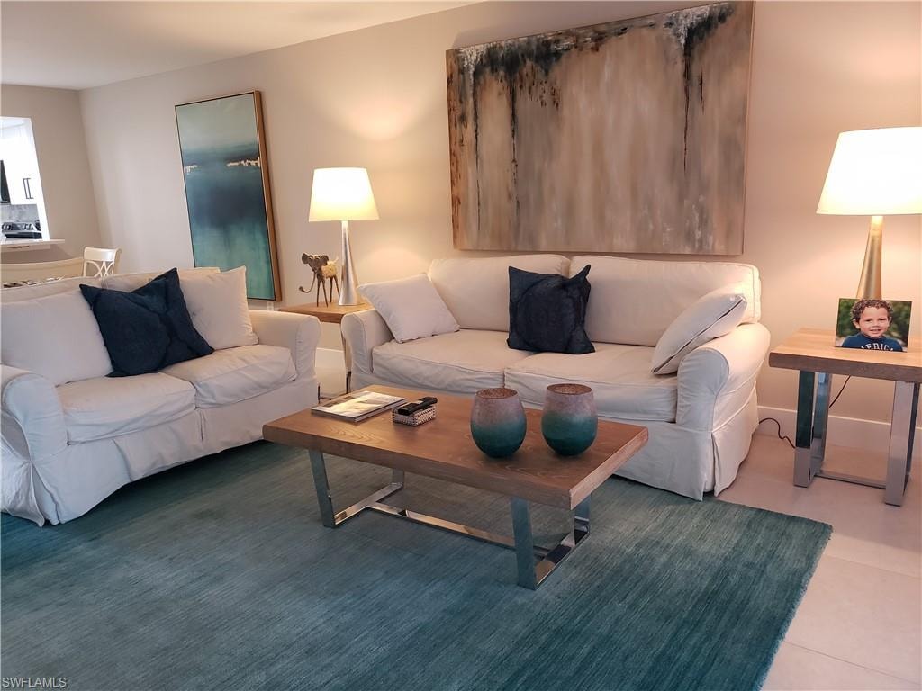 Living room features large format tile, coastal decor and amazing view of water and golf course